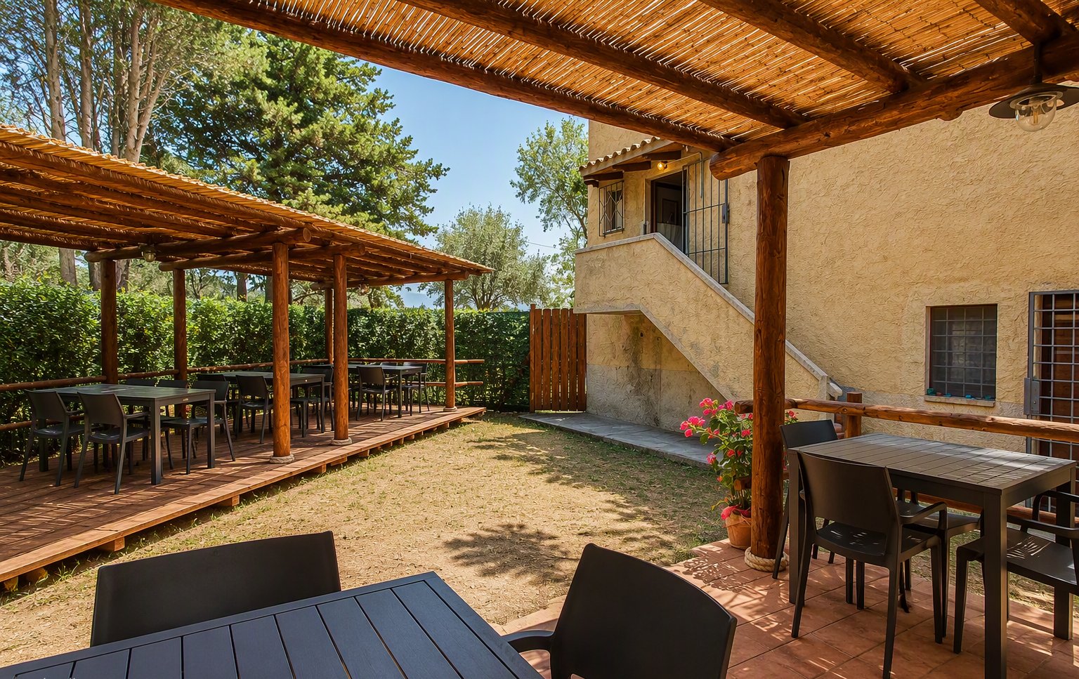Il giardino con la pergola in legno e i tavoli all'aperto